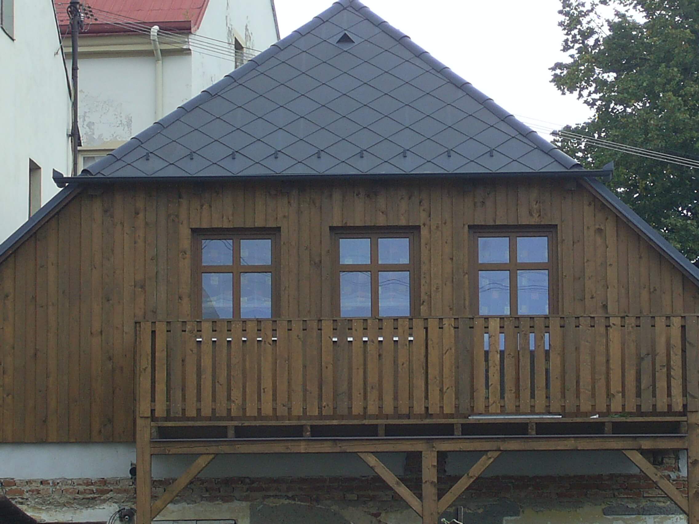 Dřevěný obklad štítu domu s balkonem